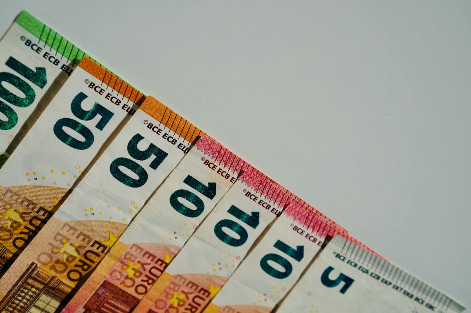 Euro banknotes fanned out in a row on a white surface