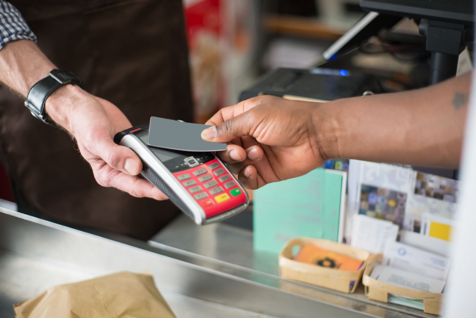 A hand holding a bank card to a contactless payment terminal