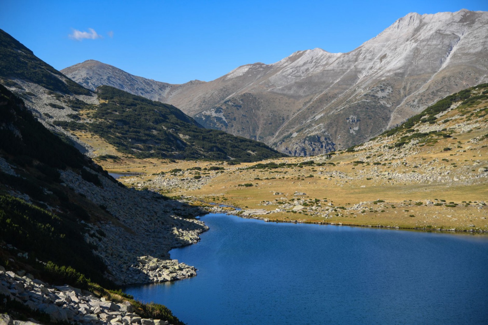 A deep blue alpine lake below bare grey peaks and open scree slopes