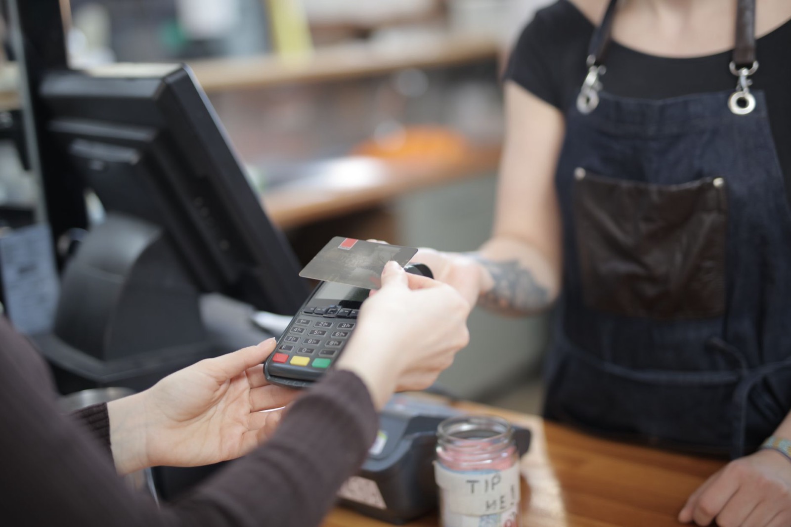 A bank card held against a card terminal across a cafe counter