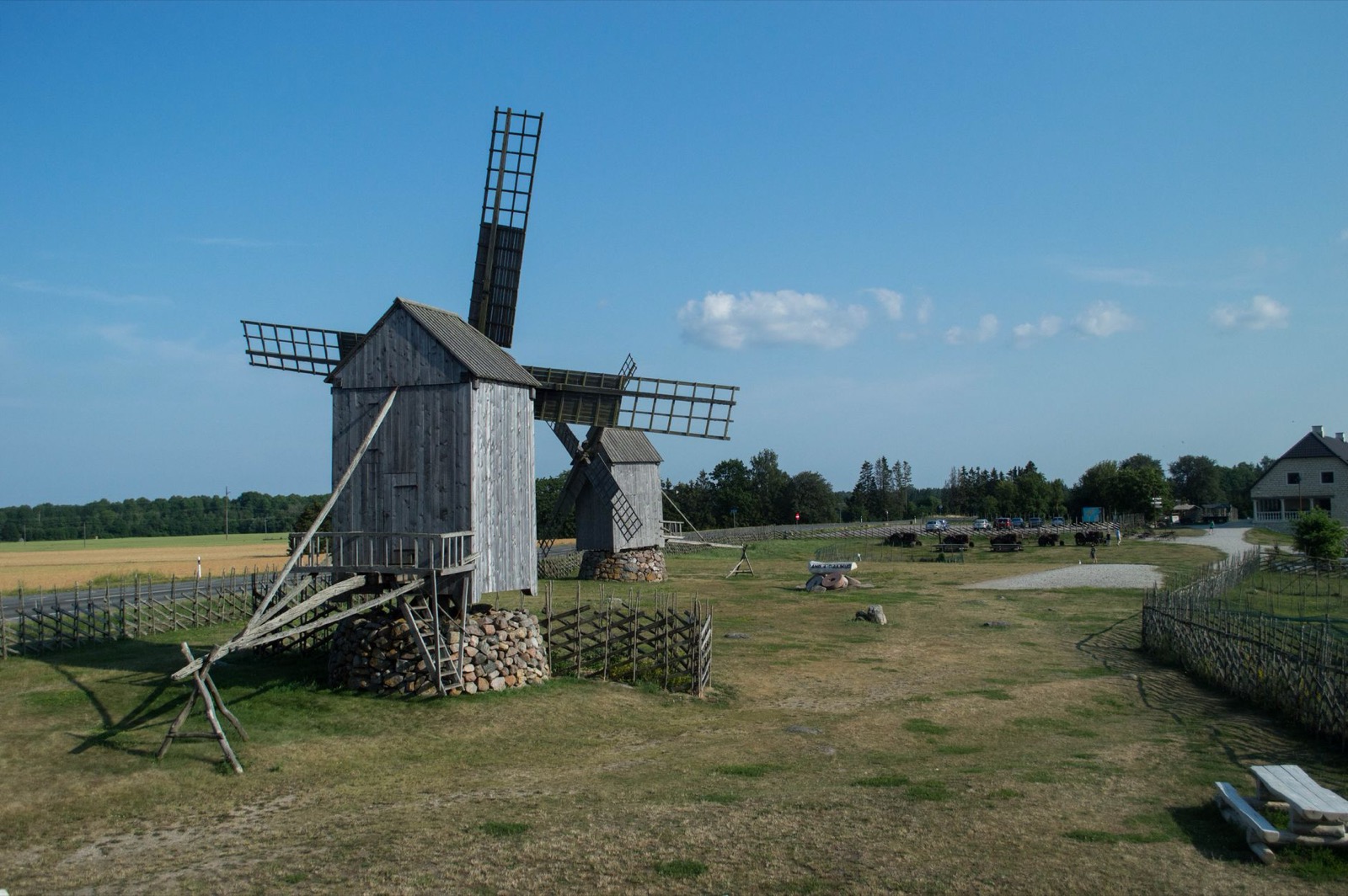 Wooden post mills standing in a row on open grassland under a blue sky