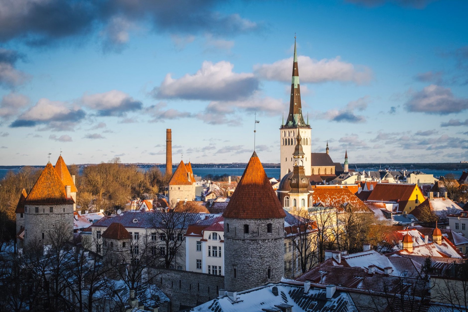Snow on the red roofs and wall towers of Tallinn old town, the sea beyond