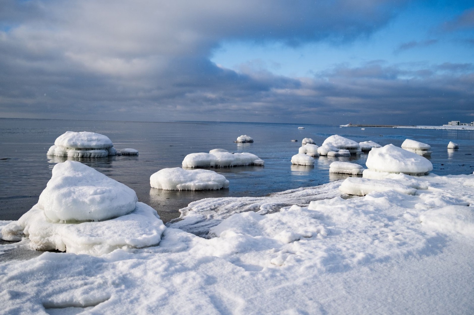 Snow-capped boulders along a frozen Baltic shore under a pale winter sky