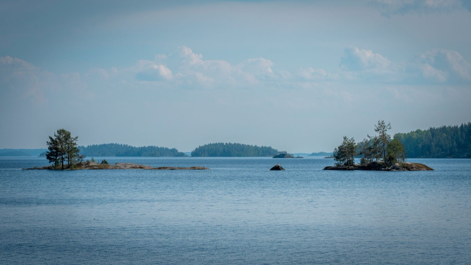 Small forested islets scattered across a wide blue lake under a pale sky