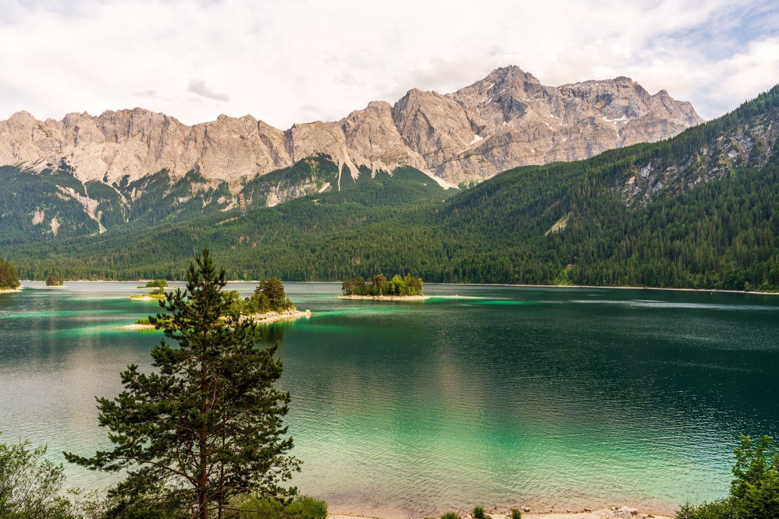 A turquoise alpine lake below steep forested mountains in the Bavarian Alps