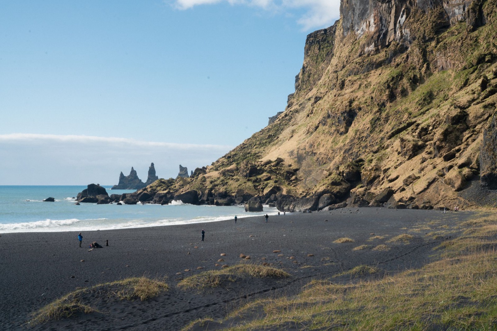 Black sand and offshore sea stacks below a steep cliff at Reynisfjara