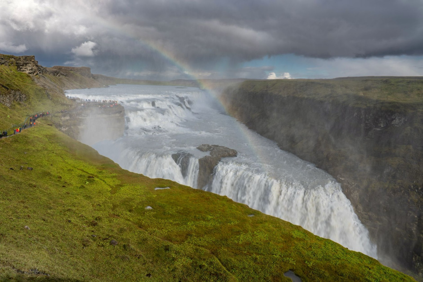 The wide two-tier falls of Gullfoss dropping into its canyon, a rainbow in the spray