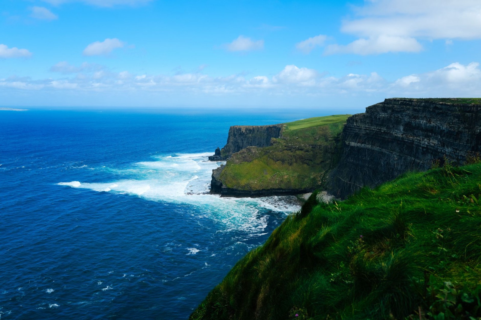 The Cliffs of Moher in County Clare dropping into the Atlantic under a bright sky