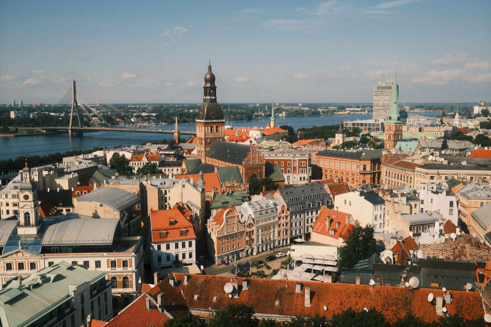The spires and red rooftops of Riga old town above the Daugava under a summer sky