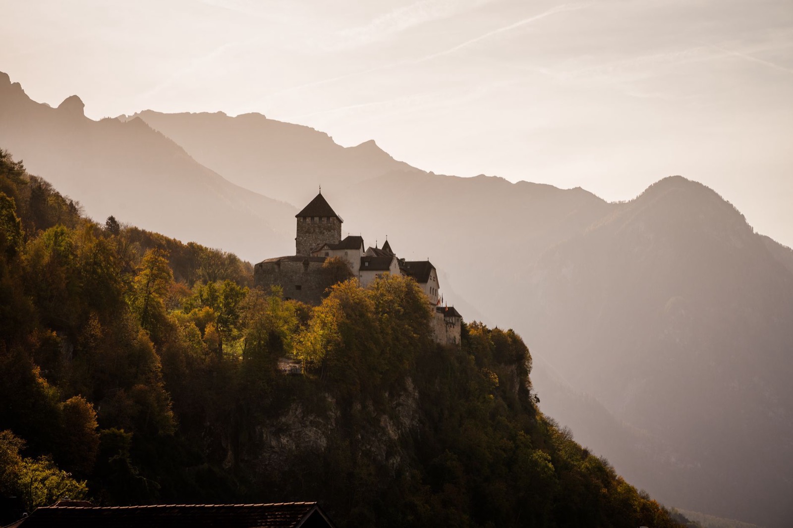 Vaduz castle on its wooded rock above the roofs of the town and the Rhine valley beyond