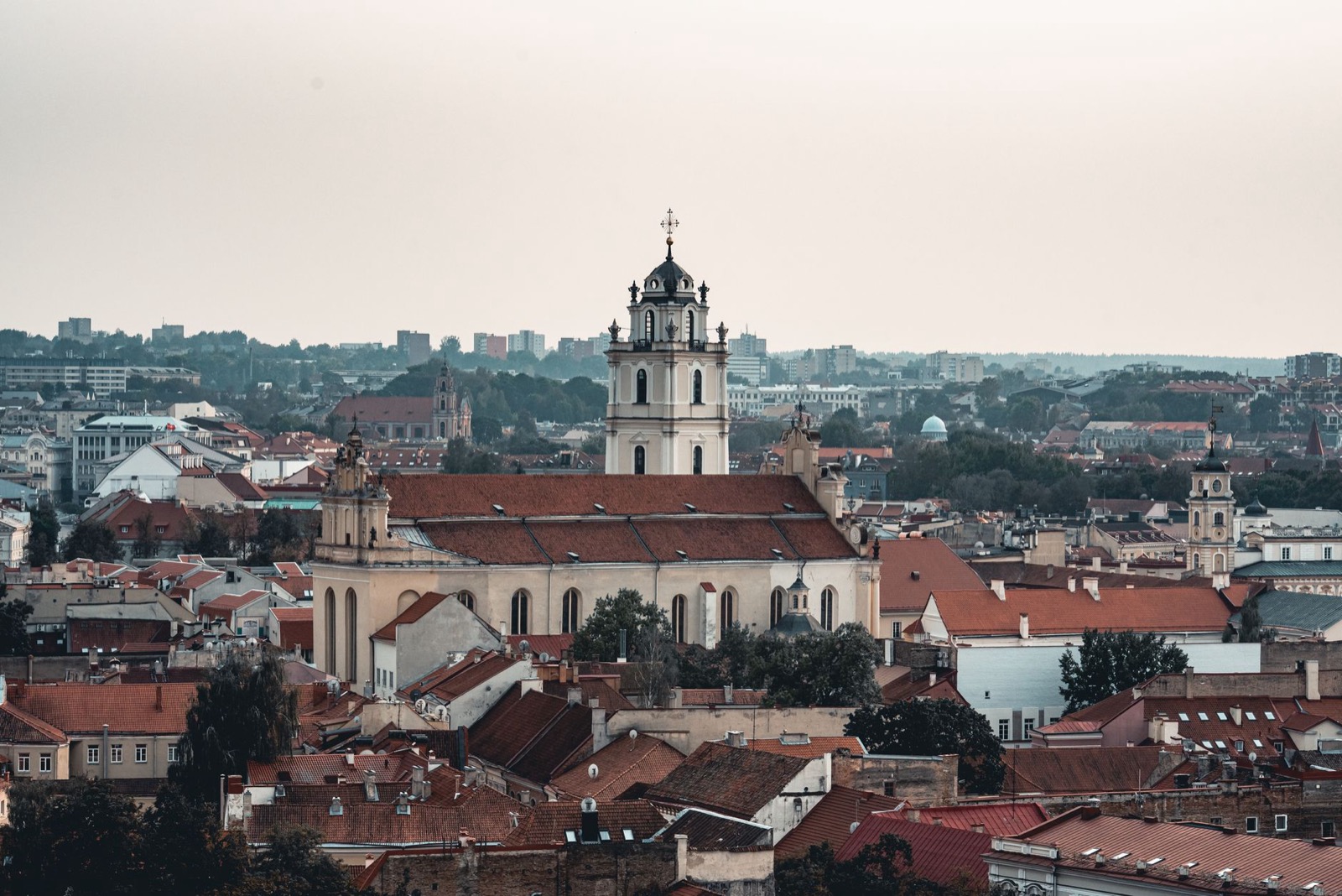Church towers and red tiled roofs spreading across Vilnius under a pale sky