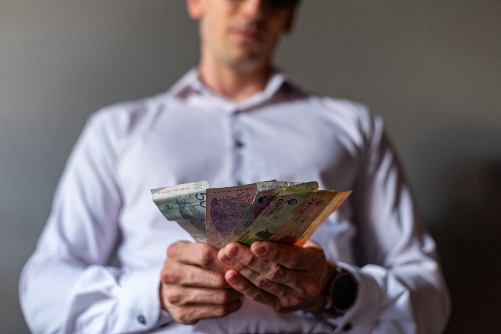 A man in a white shirt holding out a fan of banknotes