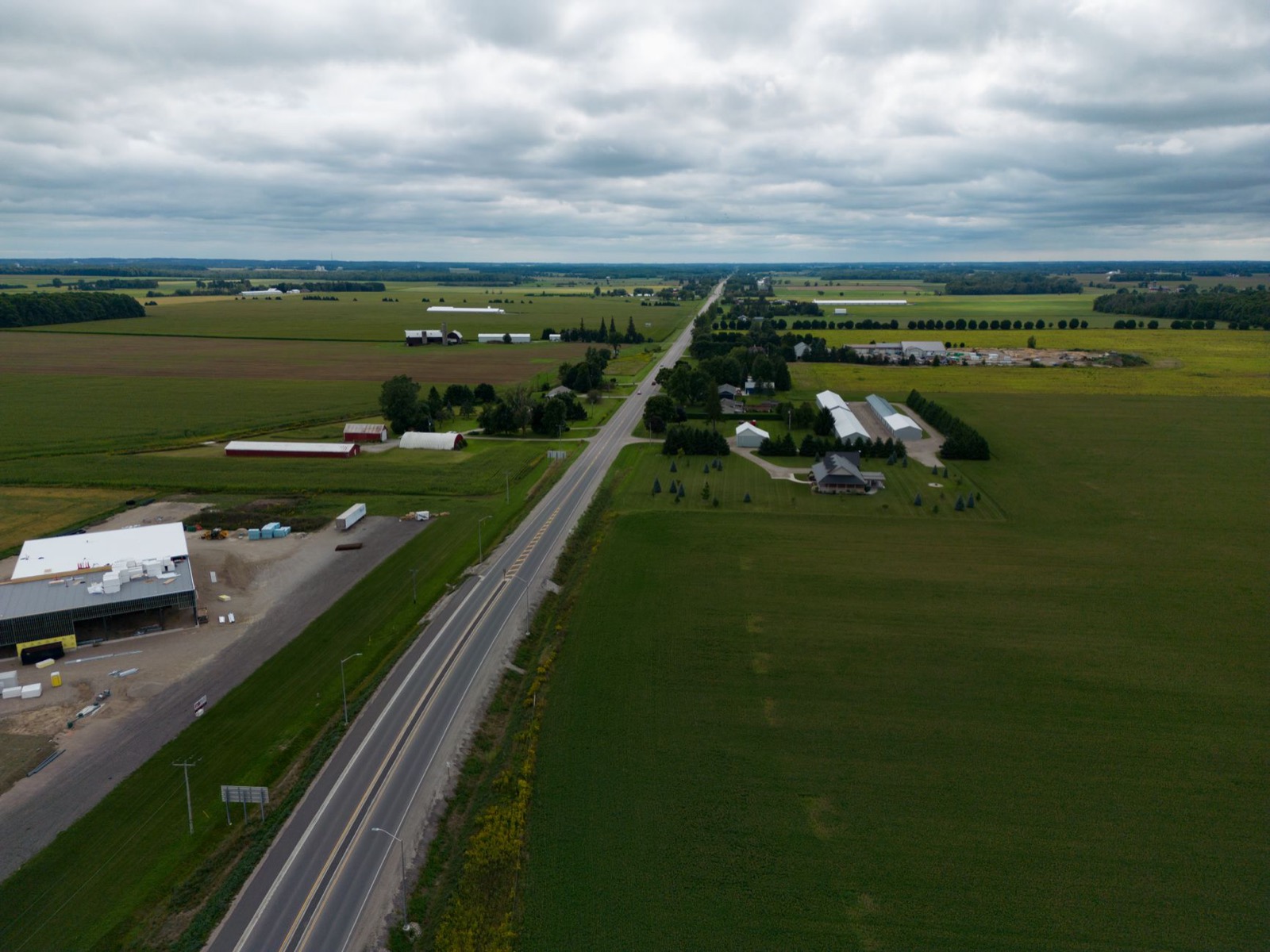 A straight two lane road running to the horizon through flat farmland, seen from above