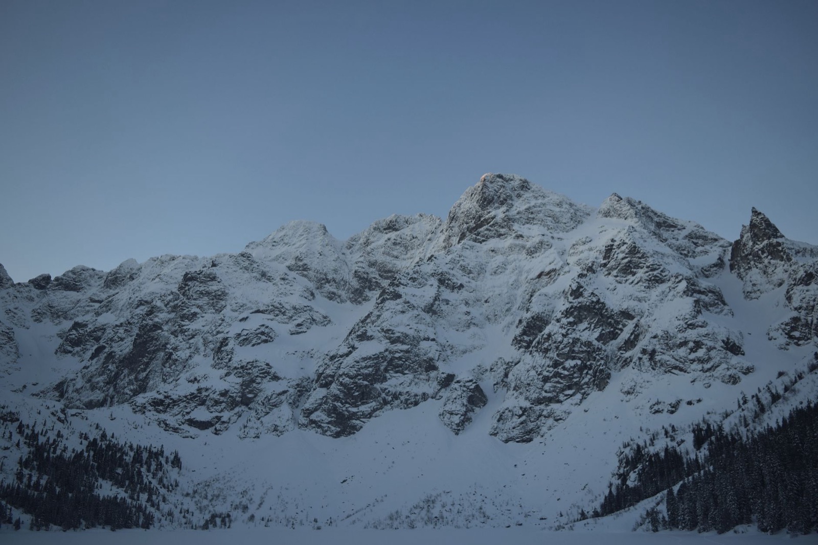 Snow covered Tatra peaks above a white valley and dark spruce forest
