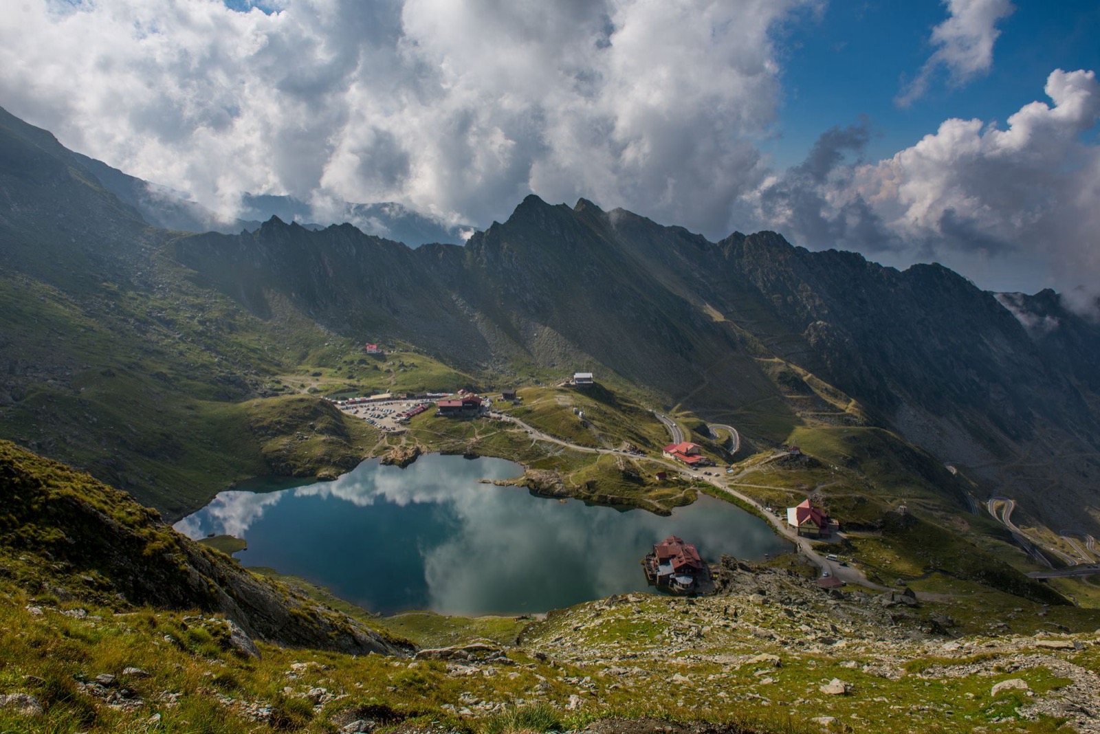 The glacial lake and chalets at Balea Lac, with the Transfagarasan switchbacking across the slopes behind