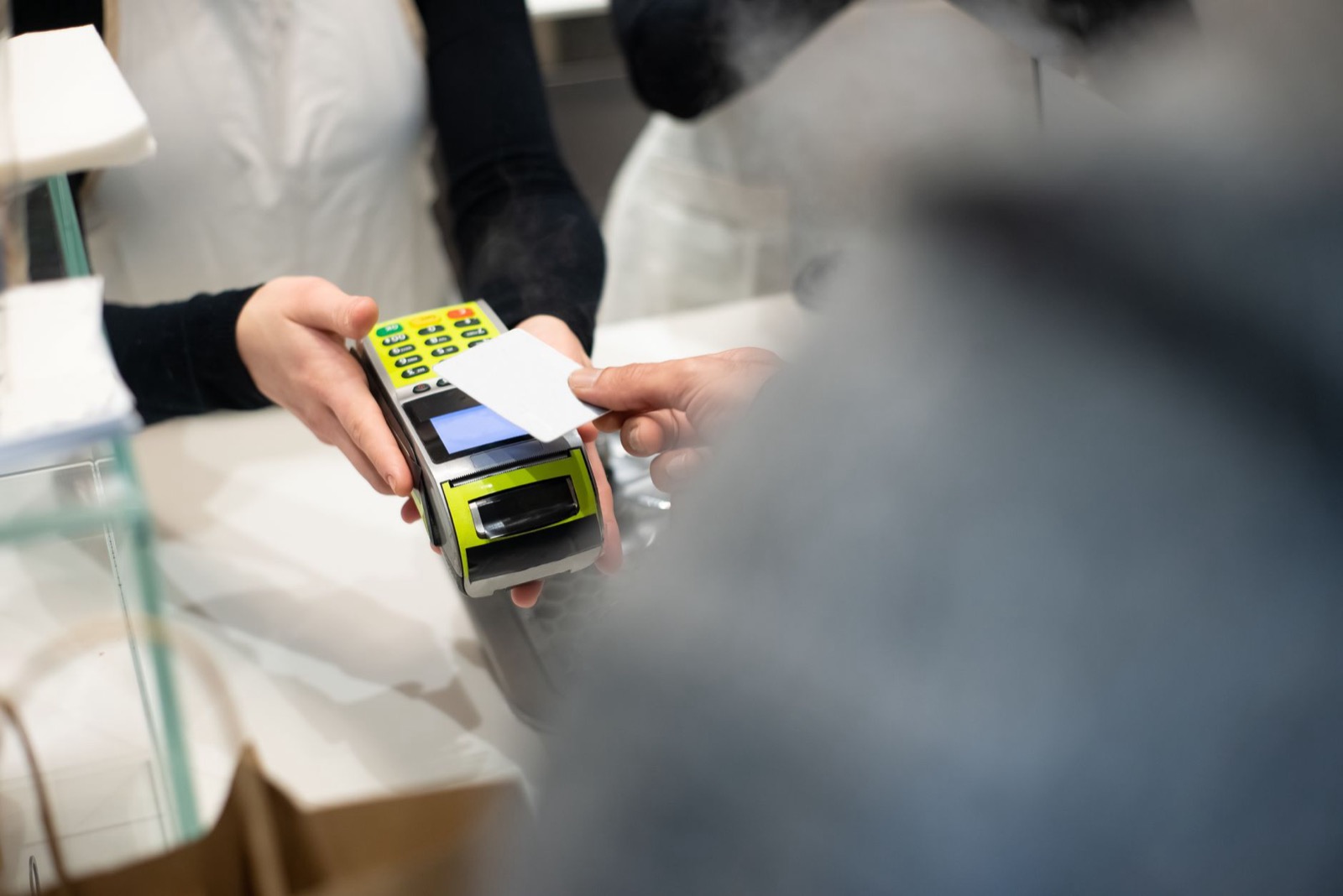 A customer paying with a bank card at a terminal on a shop counter