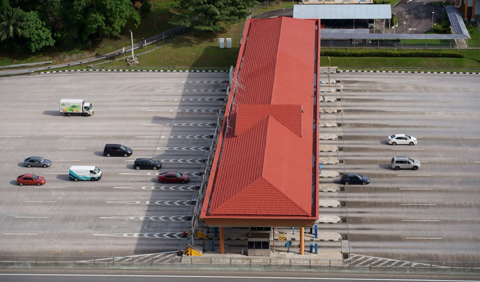 An aerial view of a motorway toll plaza with cars queuing at the open lanes