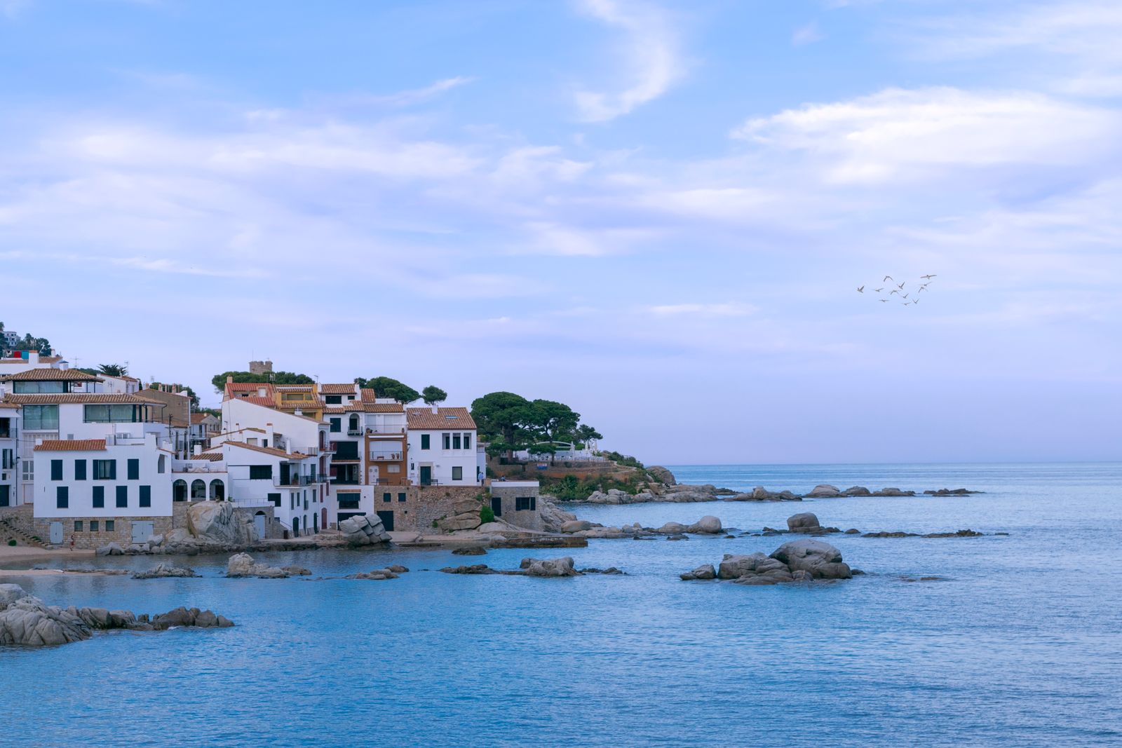 White houses above a rocky turquoise cove on the Mediterranean coast