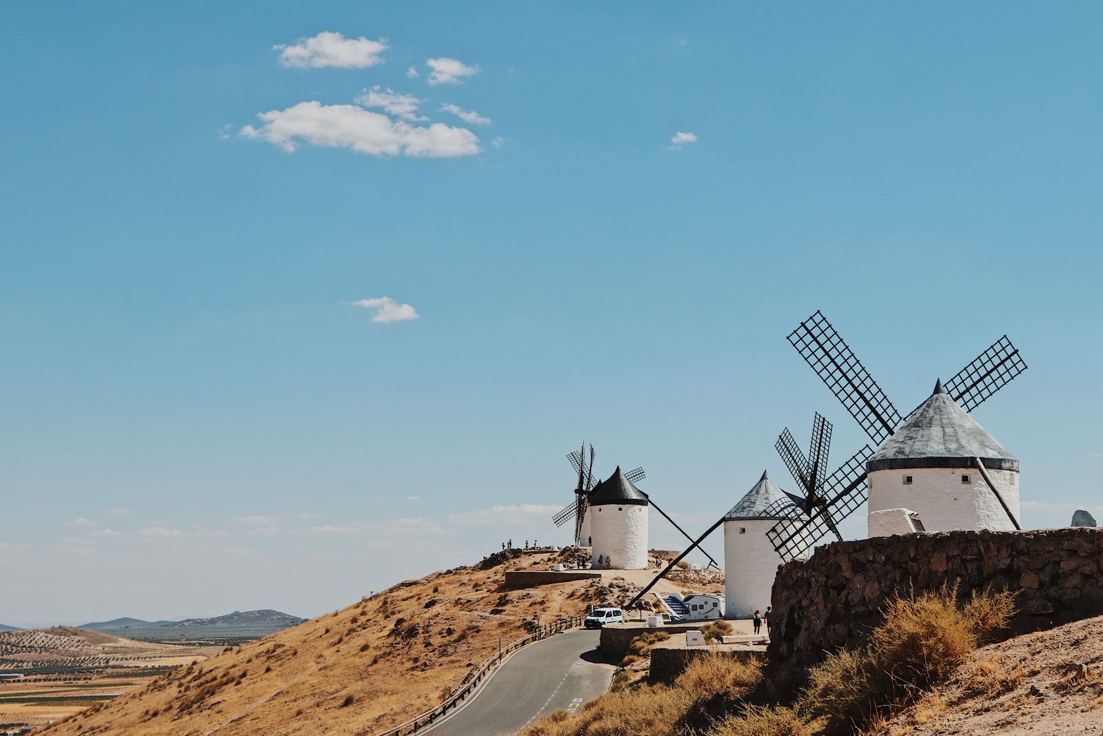 Whitewashed windmills on a dry ridge in La Mancha under a blue sky
