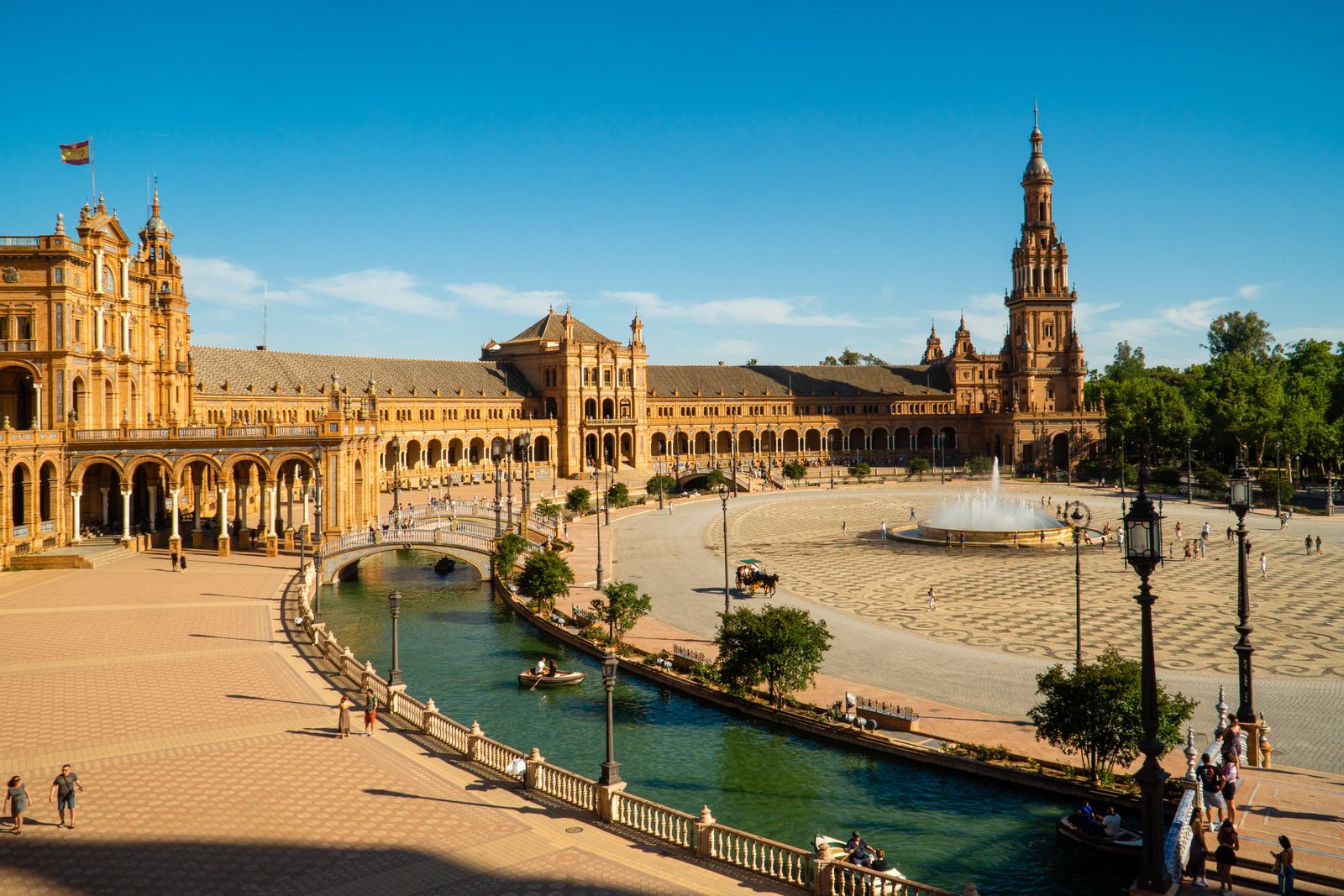 Plaza de España in Seville, its curved brick facade and canal lit by late afternoon sun