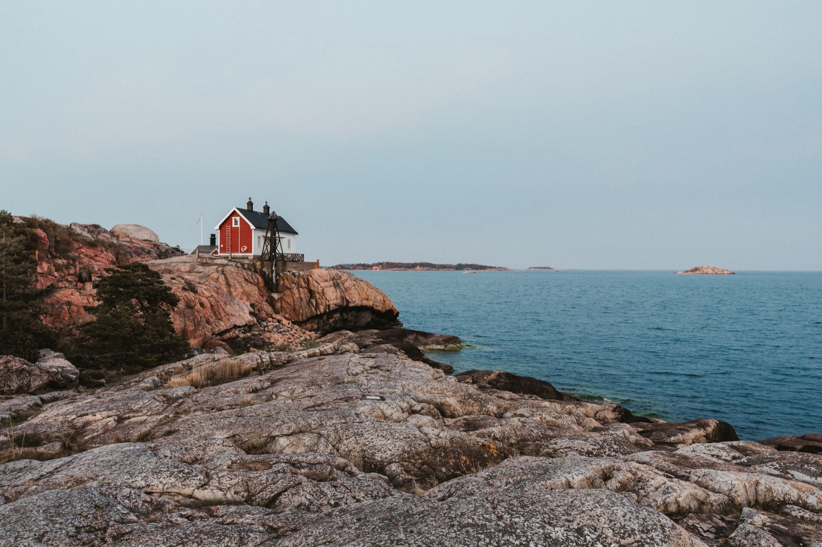 A red wooden cottage on smooth granite rock above the sea in an archipelago