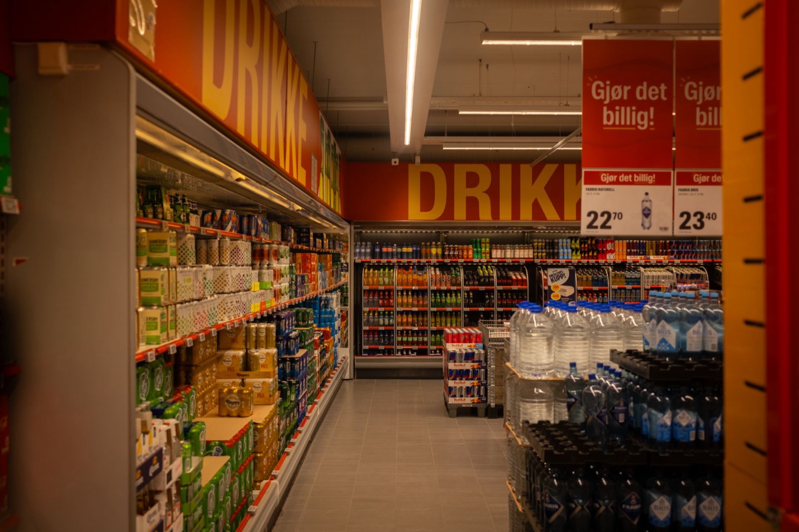 The drinks aisle of a discount supermarket with price signs hanging overhead