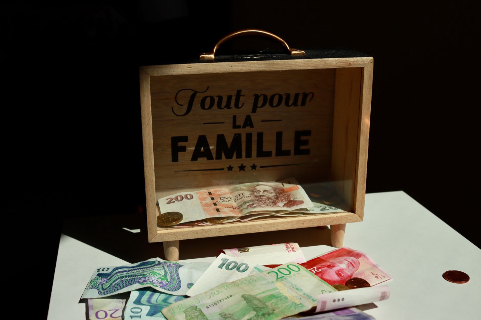 Banknotes and coins spilling out of a small wooden money box