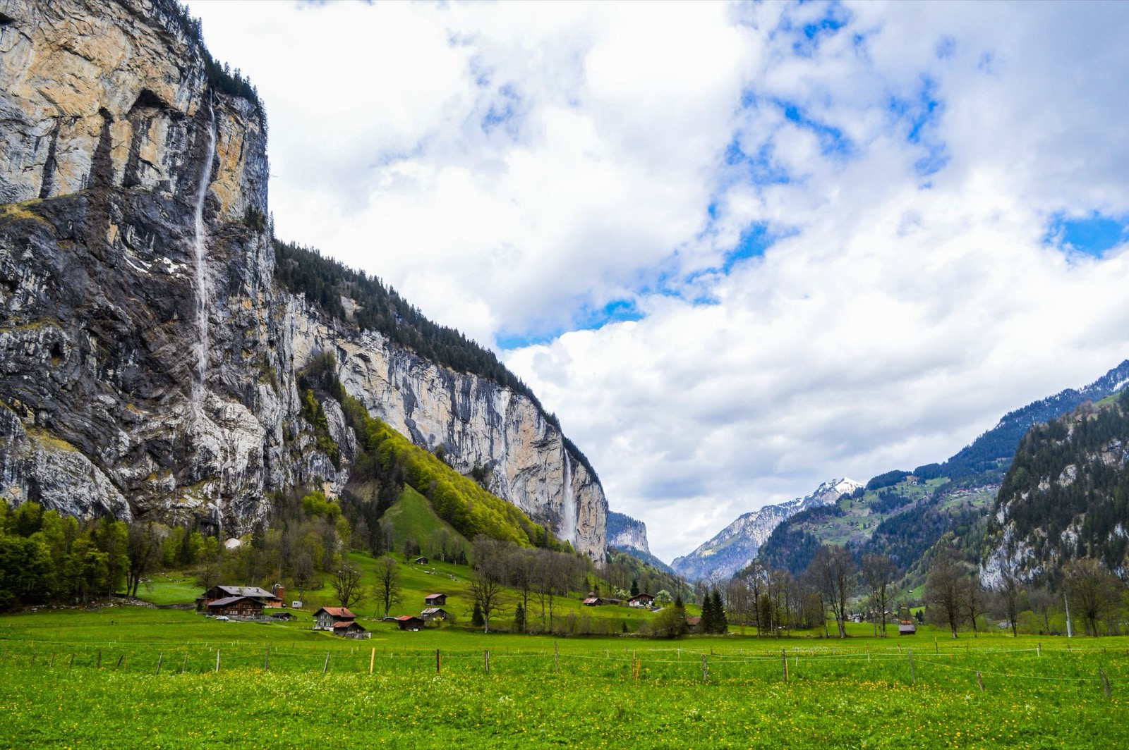 A waterfall falling from a cliff into the green Lauterbrunnen valley in the Bernese Oberland