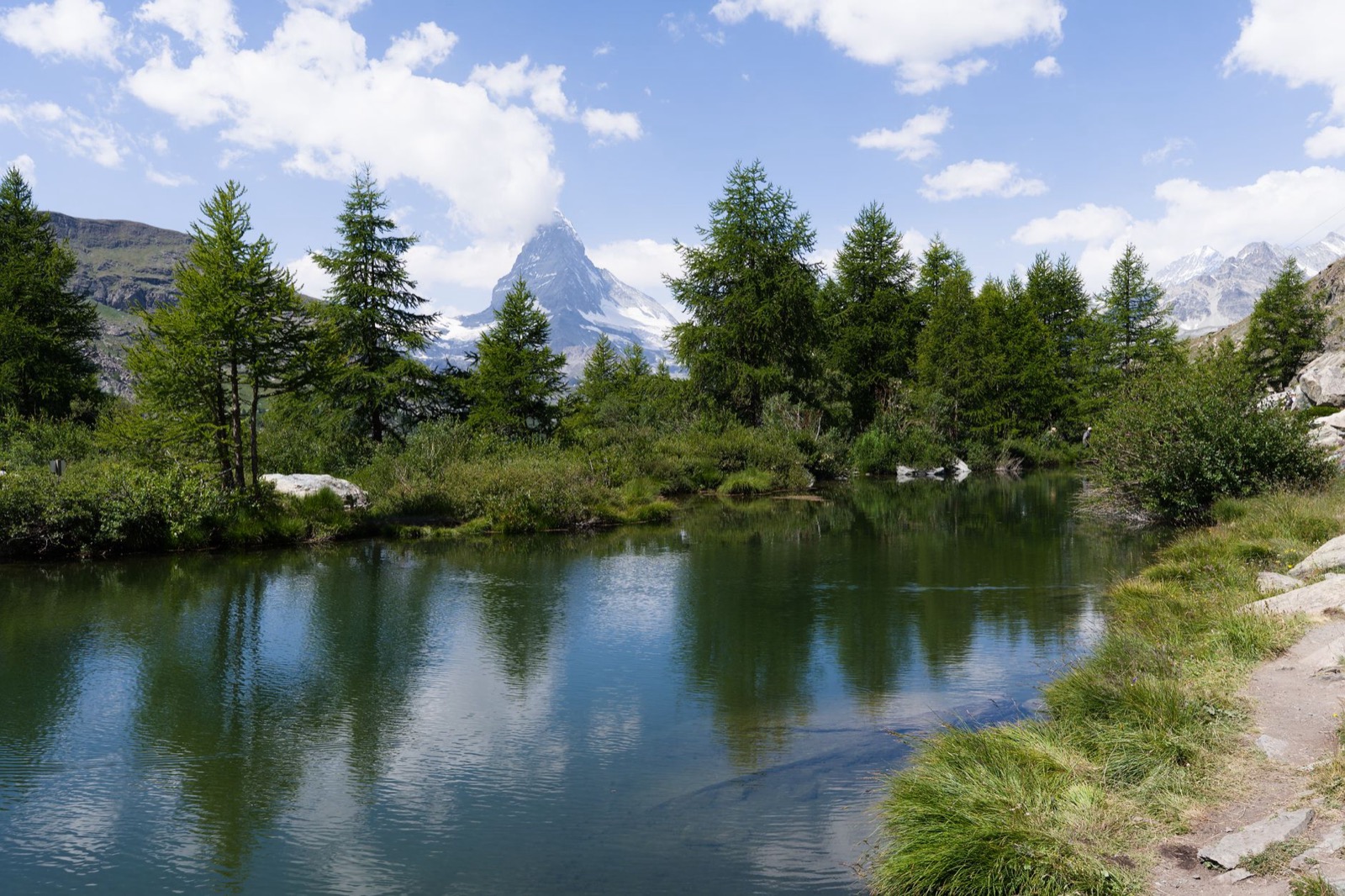 The Matterhorn rising behind larches above a still mountain tarn