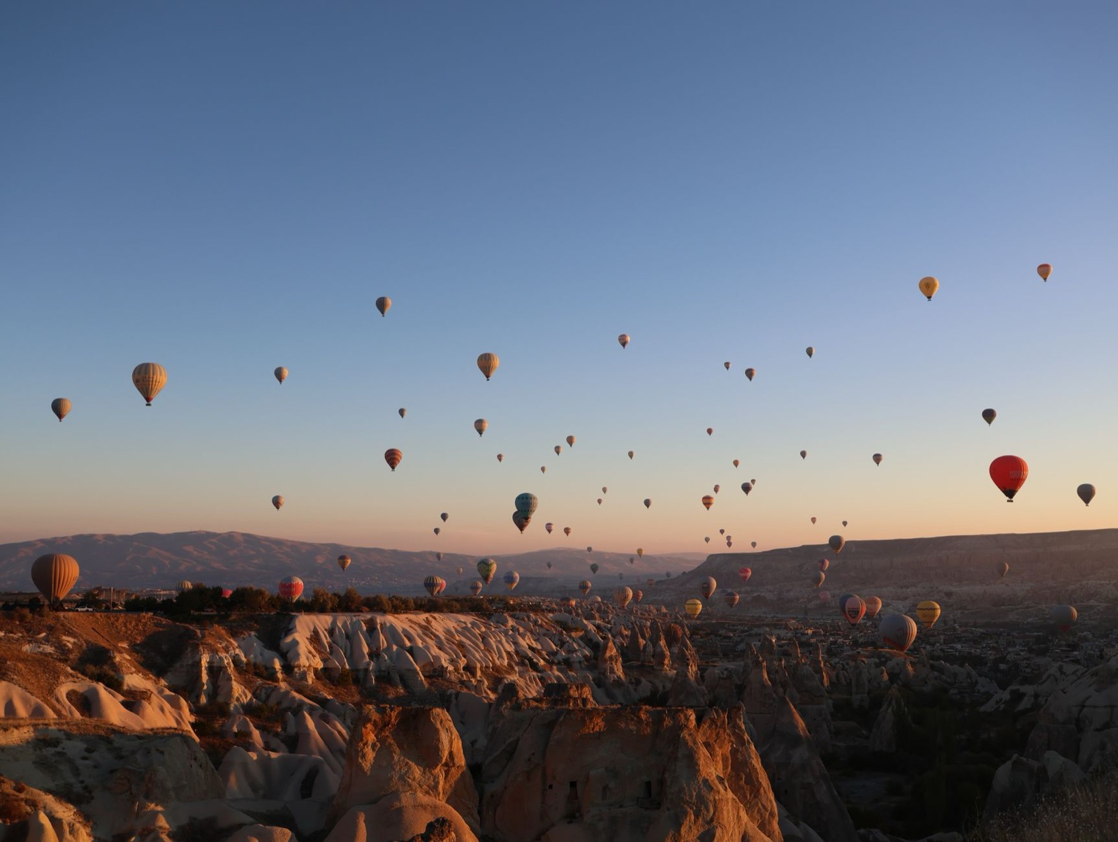 Hot air balloons rising over the fairy chimneys of Cappadocia at sunrise