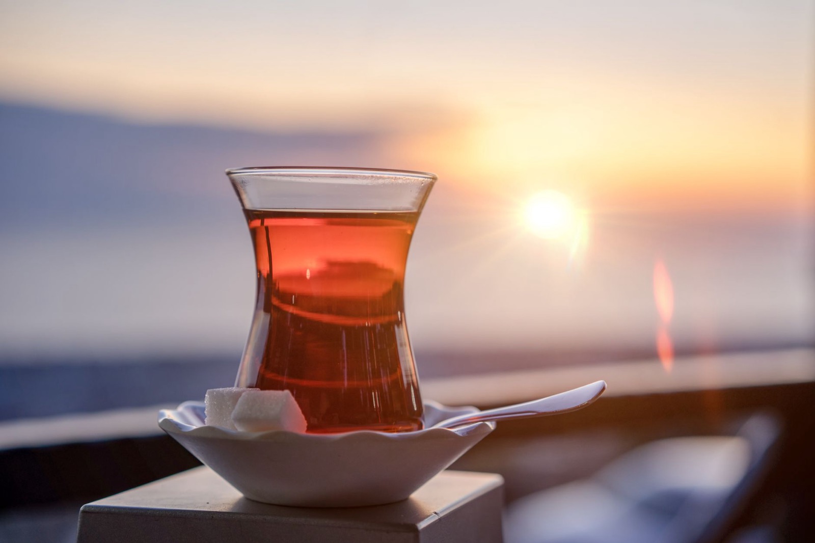 A tulip-shaped glass of Turkish tea on a saucer with sugar cubes