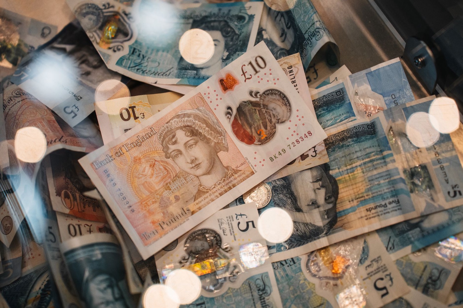 British pound coins and banknotes spread on a wooden surface