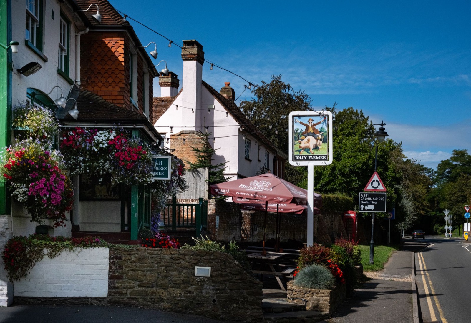 The painted front of a village pub with hanging flower baskets and a chalkboard outside