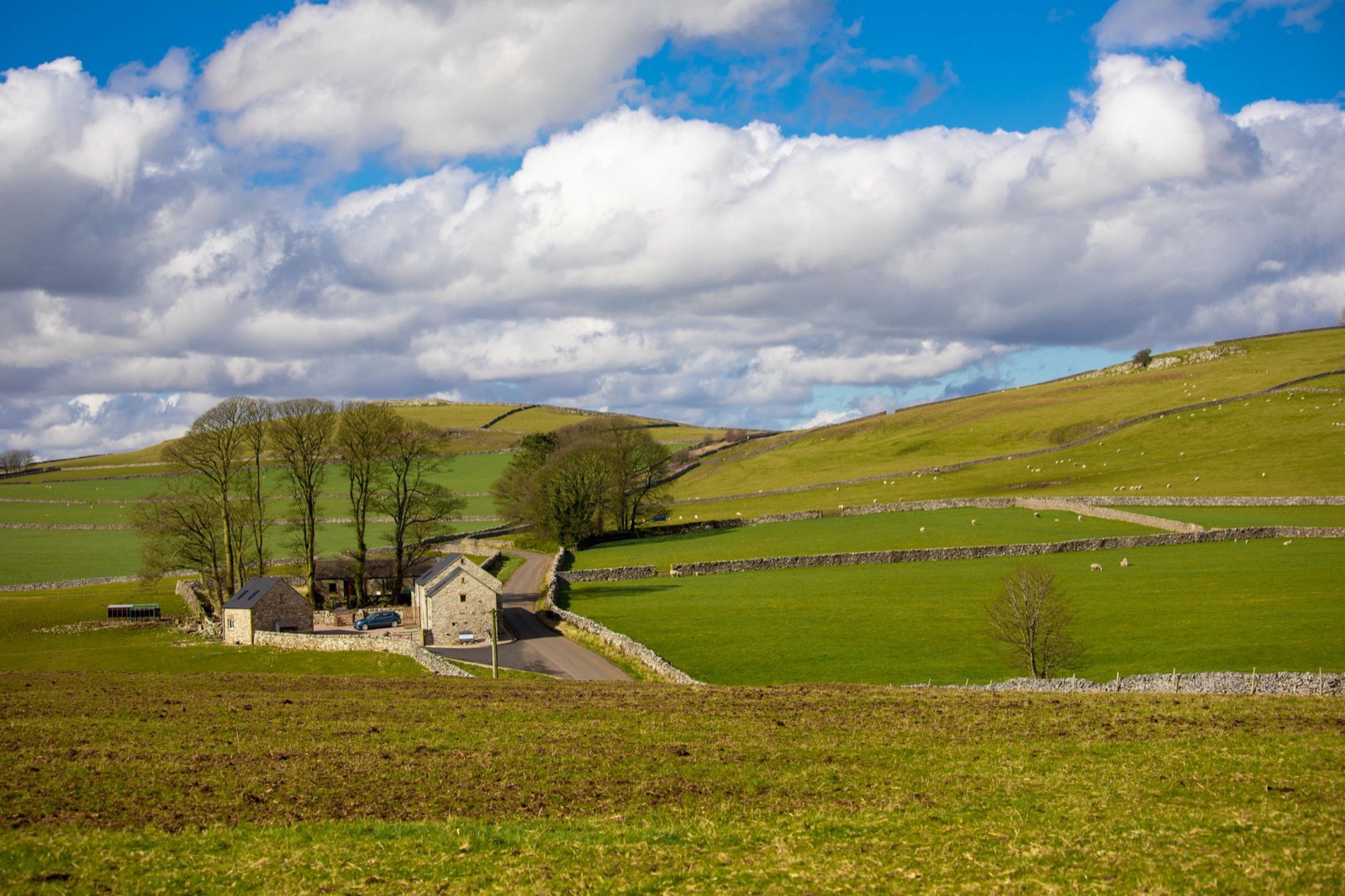 Low grey cloud breaking over a green valley and a stone wall in northern England